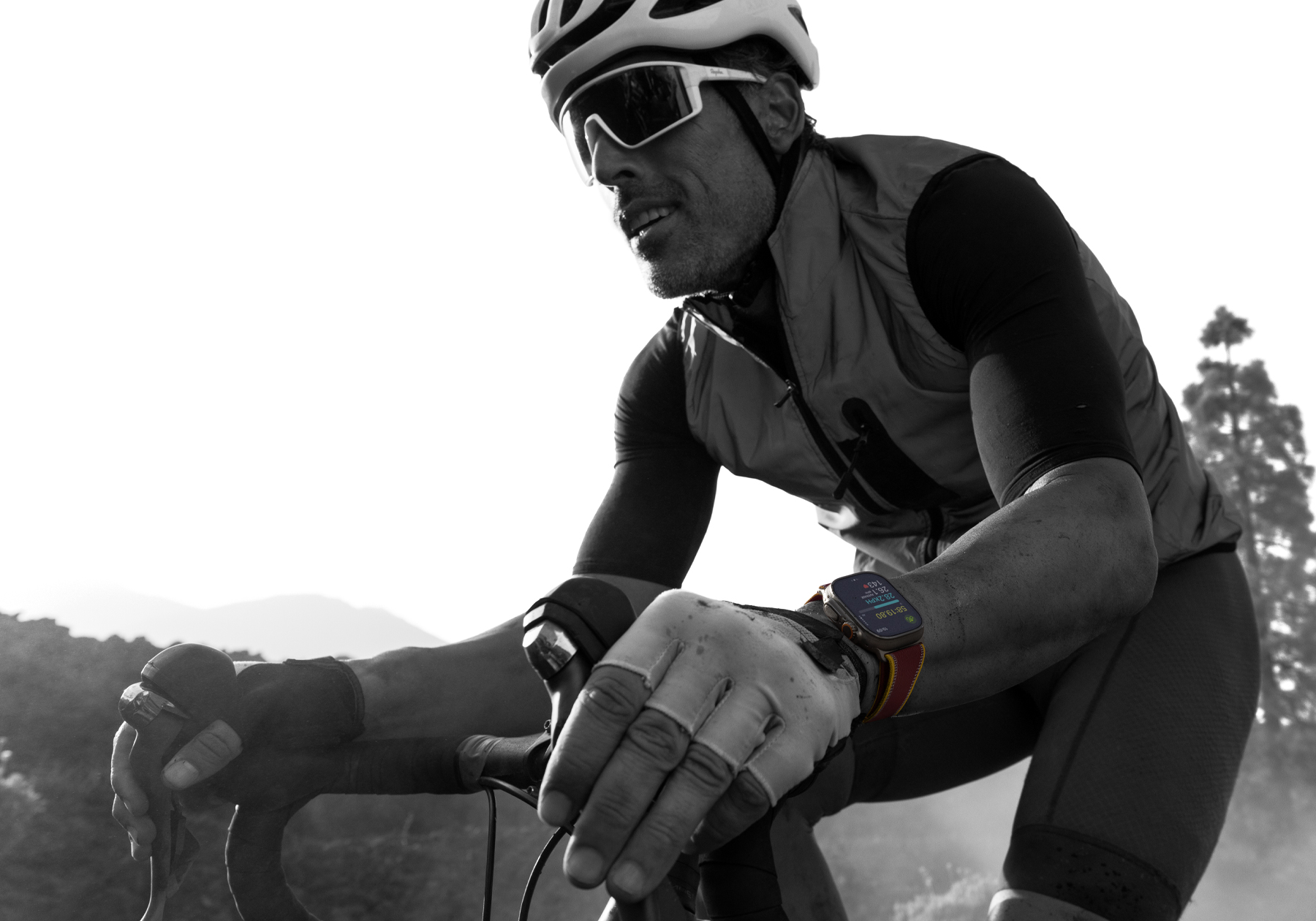 A person riding a road bike while wearing Apple Watch Ultra 4, screen shows cycling metrics