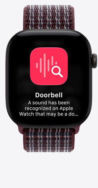 Apple Watch Series 12, na displeji je vidět rozpoznávání zvuku u dveří, hliníkové pouzdro, černá barva, připojené k provlékacím sportovnímu řemínku, vínově ruměná kvapalinová barva