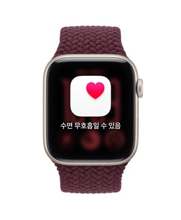 Apple Watch SE 3, 스타라이트 색상 알루미늄 케이스 및 건강 추적(수면 무호흡일 수 있음 알림)이 표시되고, 오른쪽 옆면 외관에 Digital Crown 다이얼이 보이는 모습. 버건디 색상 브레이드 스포츠 루프 밴드의 모습