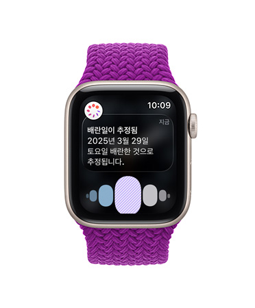 배란일 추정 알림이 나와 있고 오른쪽 옆면 외관에 Digital Crown이 보이는 로즈 골드 색상 알루미늄 케이스의 Apple Watch Series 11, 그리고 라이트 블러시 스포츠 밴드