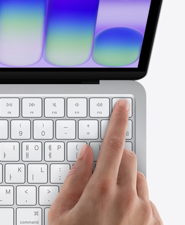 실버 색상 MacBook Neo에서 키보드 오른쪽 상단의 Touch ID 센서에 손가락을 대고 있는 모습