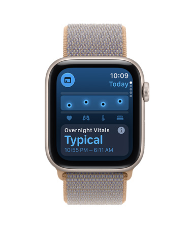 Apple Watch SE 3 z aluminiową kopertą w kolorze księżycowej poświaty i opaską sportową w kolorze dżinsu (jasnoniebiesko-szarym). Ekran pokazuje parametry życiowe. Na prawym boku urządzenia pokrętło Digital Crown