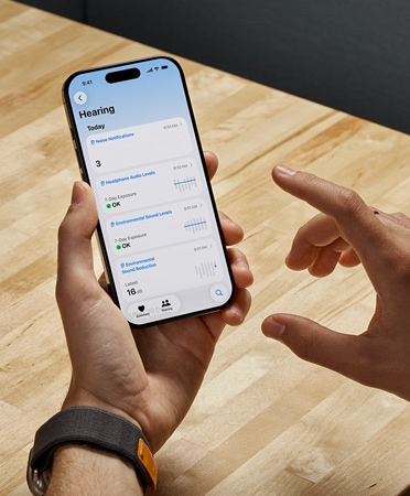 Osoba używająca AirPods Pro 2 trzyma iPhone’a, korzystając z nowej funkcji Badanie słuchu