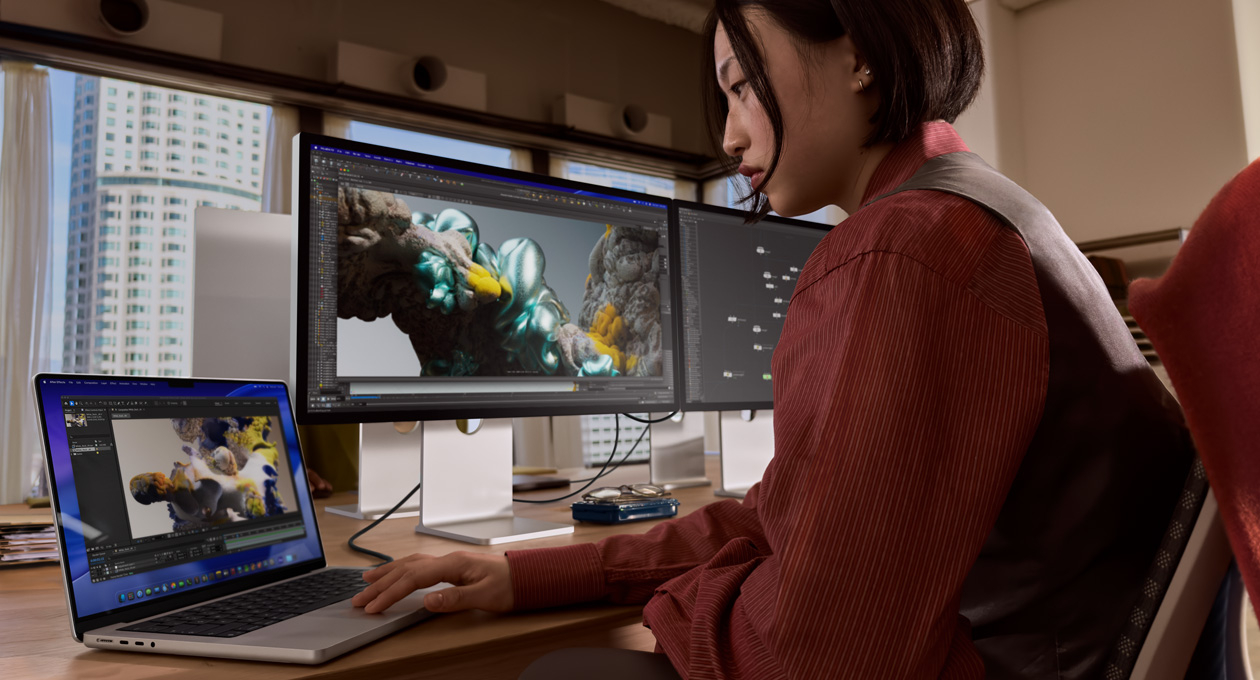 O persoană într-un cadru de birou lucrează pe un laptop MacBook care este conectat la Studio Display XDR printr-un port Thunderbolt 5