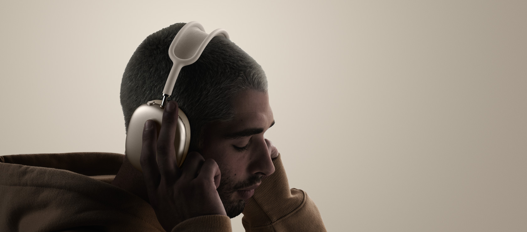 Inimene kandmas AirPods Max 2 kõrvaklappe, külgvaade, puudutamas kõrvapatju