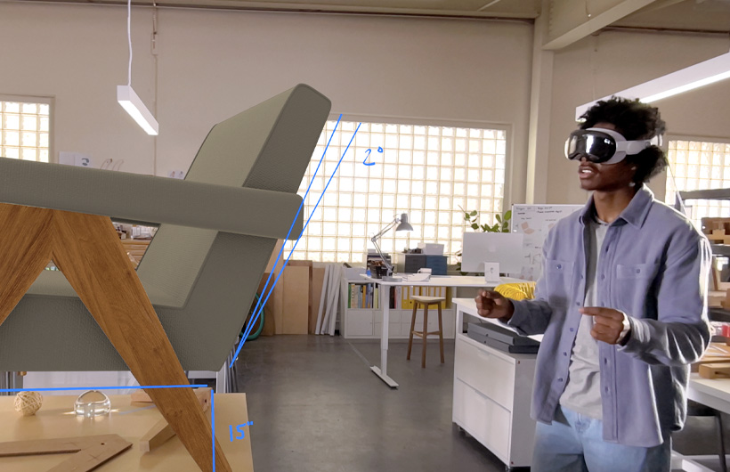 Une personne portant l’Apple Vision Pro mesure la projection 3D d’une chaise avec des gestes de la main