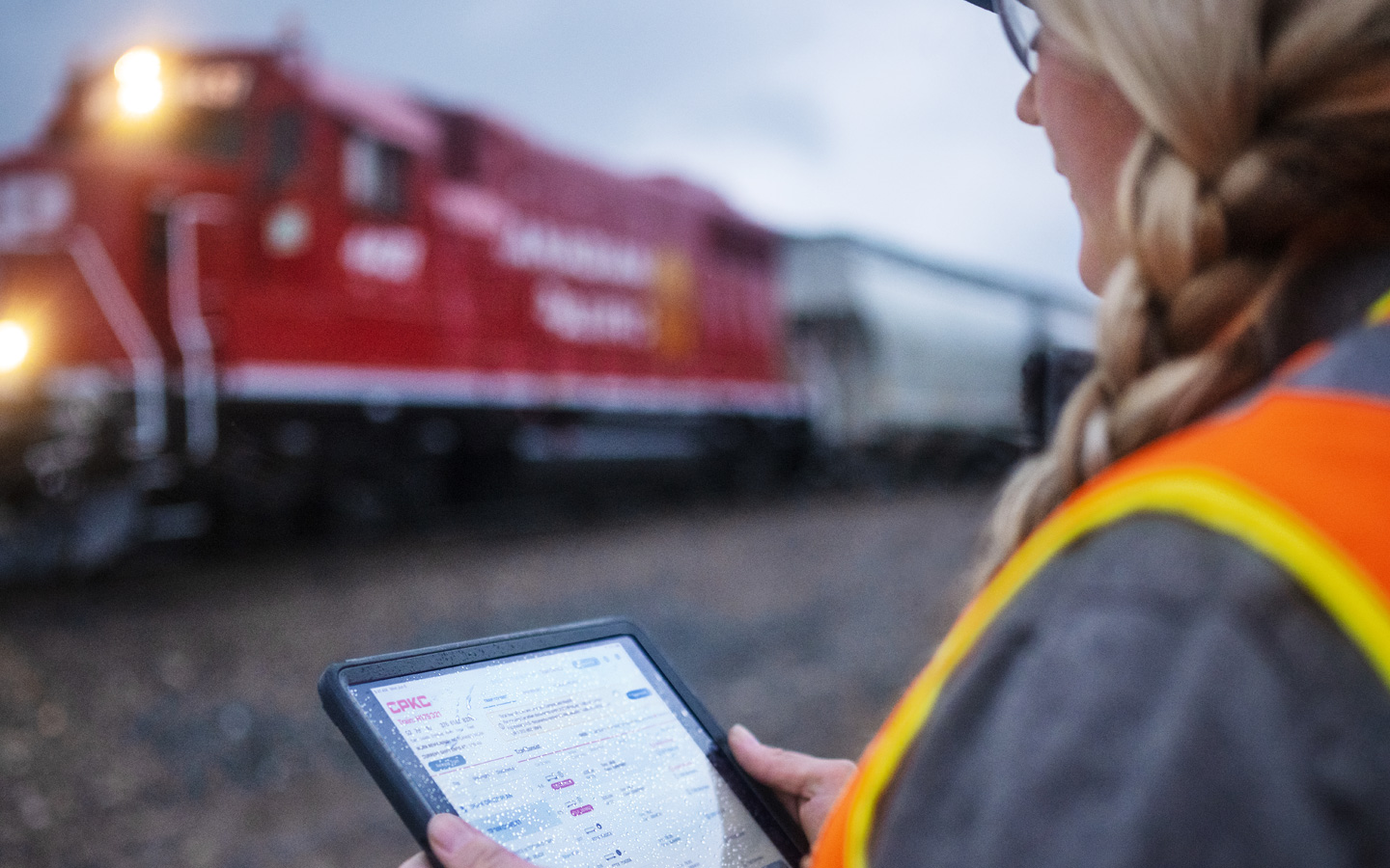 En jernbanearbejder læser togplaner på iPad, mens han står på en banegård