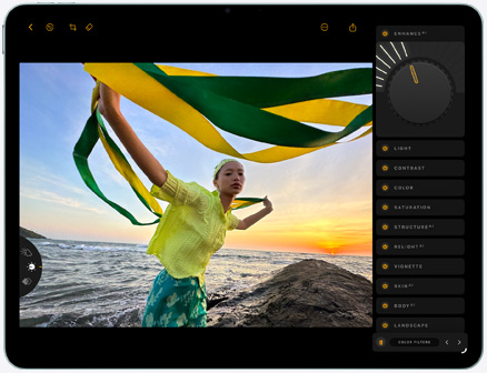iPad Air, Vorderseite, Bearbeitung eines Fotos einer Person, die vor dem Hintergrund eines Sonnenuntergangs am Meer ein grünes und ein gelbes Tuch hält, mit Bearbeitungswerkzeugen auf der rechten Seite