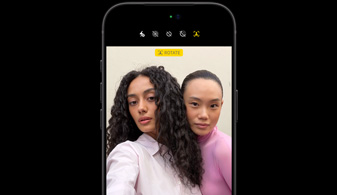 Fekete iPhone 18 Pro elölnézetből, a kijelzőjén az arckövető funkció két ember arcát mutatja, bemutatva a Center Stage előlapi kamera működését